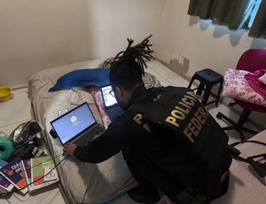 Agente da PF vasculha laptop de suspeito em busca de imagens de abuso sexual infantil — Foto: Divulgação PF